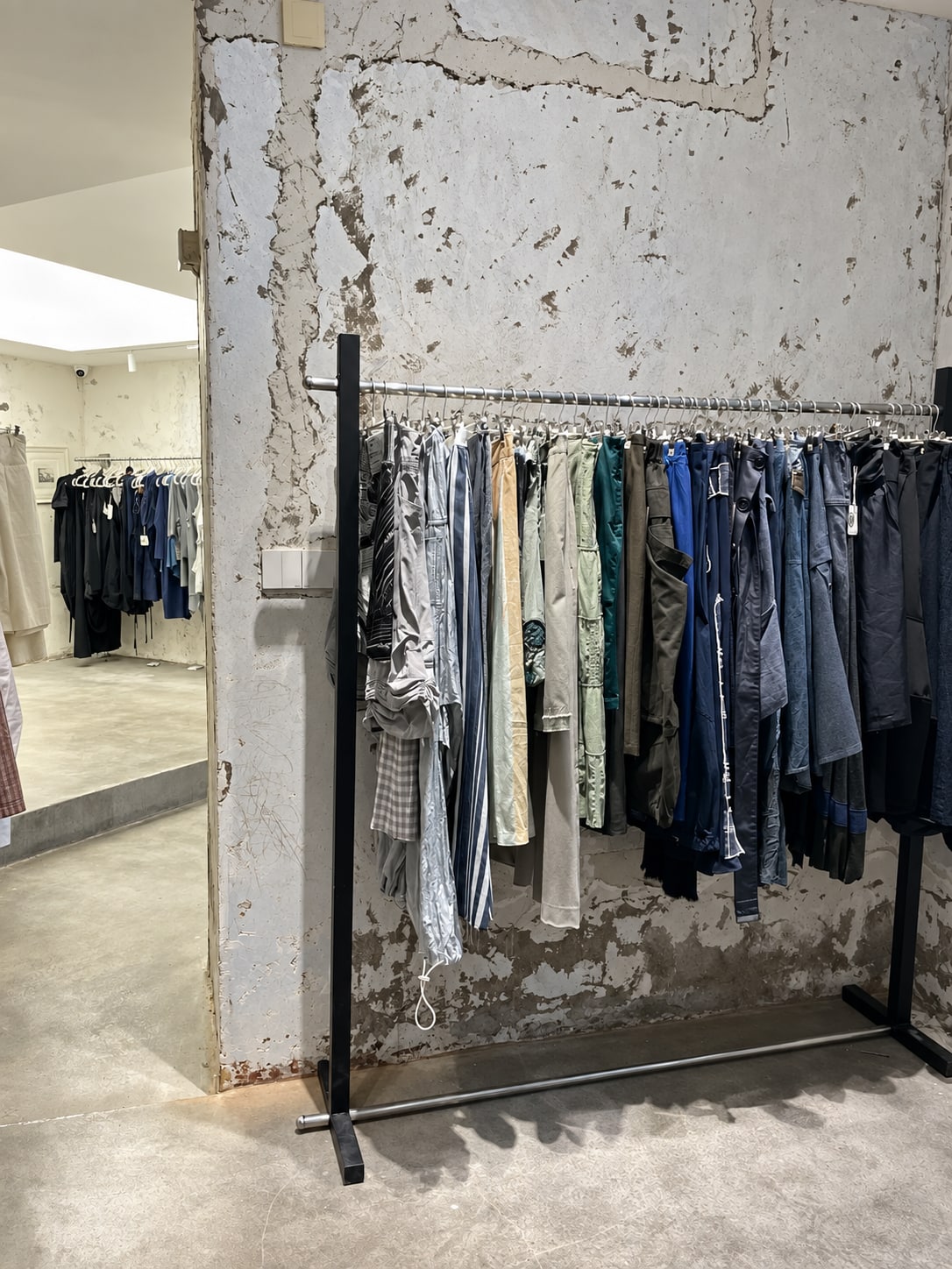 A selection of trousers on a rail against a textured wall inside HODAKYEE